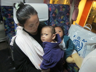 Ma Lay Lay, the 100,000th refugee assisted to resettle by IOM Thailand, and her children Labur Paw (3) and Ywar Mar Ser (11 months) on the bus before their early-morning flight from Bangkok International Airport. © IOM 2012