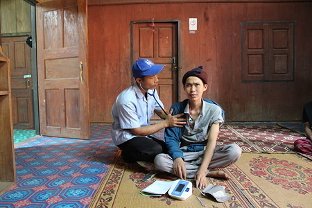 IOM community health worker Sirichai Rathkhetbanpoot (35) examines Wirasat Kirnapa (33), who has cancer and tuberculosis. He lives in Ban Huay San, close to Thaliand’s border with Myanmar. The nearest hospital is over one hour’s drive away across mountain roads. Photo IOM/Joe Lowry 2013
