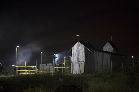The church is closed at night. Most of the worshipers are Eritreans and Ethiopians. A mass is held inside its plastic walls every Sunday. Faith is a very important part of many of those who now call this place their home, albeit a temporary one, as many of them hope. © IOM/Amanda Nero 2015

At night, the ‘New Jungle’, the informal migrant and refugee settlement in the port city of Calais, France, comes to life. Several improvised bars, restaurants and shops open after sunset. Its residents gather together to dance, play games, drink and eat. Some make bonfires and chat outside, others play football, and traditional music floats in the air.