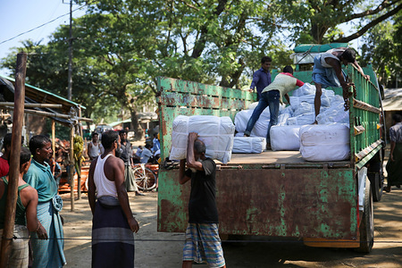 Rohingya refugees working for IOM unload aid items to be distributed to fellow refugees in Balukhali, Cox's Bazar, Bangladesh.