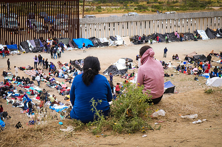 Women looking at the camp set up between the border walls that separate San Diego from Tijuana, Mexico